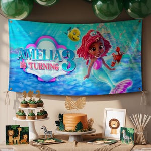 May include: A birthday party scene with a banner featuring a mermaid and the text "AMELIA IS TURNING 3". The scene includes a cake, cupcakes, and decorations with a jungle theme. Green balloons are at the top.