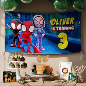 K&ouml;nnte beinhalten: Geburtstagsszene mit einem Banner mit Spider-Man-Charakteren und dem Text "Oliver wird 3". Ein Kuchen, Cupcakes und Dekorationen zum Thema Tiere sind ausgestellt. Gr&uuml;ne Luftballons sind &uuml;ber der Szene aufgeh&auml;ngt.