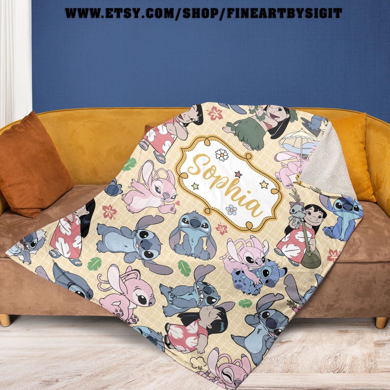 Puede incluir: Una manta de felpa con un patr&oacute;n repetido de personajes de dibujos animados en tonos azules, rosas y verdes sobre un fondo amarillo claro. La manta tiene una etiqueta personalizada con el nombre "Sophia". La URL de la tienda Etsy es visible en la parte superior.