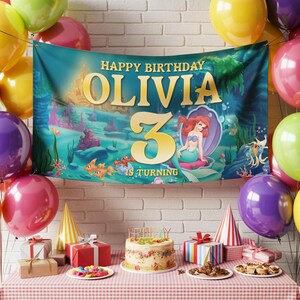 May include: A birthday party scene with a banner that reads "Happy Birthday Olivia 3 is Turning." The banner features an underwater theme with a mermaid illustration. Colorful balloons, gifts, a cake, and party hats are on a table.