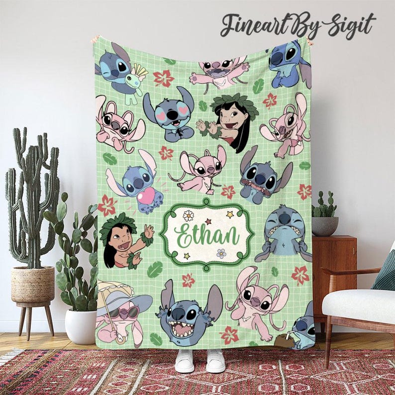 May include: A light green blanket featuring cartoon characters in various poses, with red and pink floral accents. The blanket has the name "Ethan" in a decorative frame. The blanket is made of a soft material.