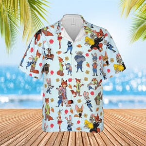 May include: A light blue short-sleeve button-down shirt featuring an all-over print of various cartoon characters, including foxes and rabbits, interspersed with small orange carrot icons and yellow police badge symbols across the fabric.