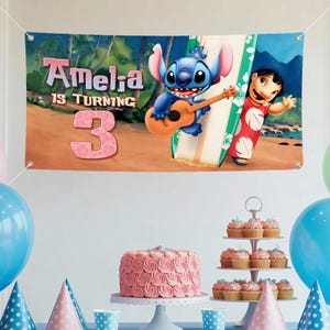 May include: A birthday banner with Stitch playing a ukulele, Lilo, and the text "Amelia is turning 3." The banner has a tropical beach scene background. The scene includes a cake, cupcakes, and balloons.
