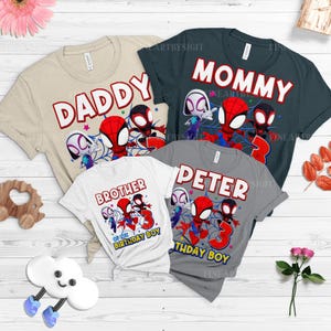 K&ouml;nnte beinhalten: Vier kurz&auml;rmelige T-Shirts mit Superhelden-Grafiken. Die Shirts sind beige, marineblau, wei&szlig; und grau. Auf den Shirts steht "Daddy", "Mommy", "Brother of the Birthday Boy" und "Peter Birthday Boy". Jedes Shirt hat ein Spider-Man-Thema.