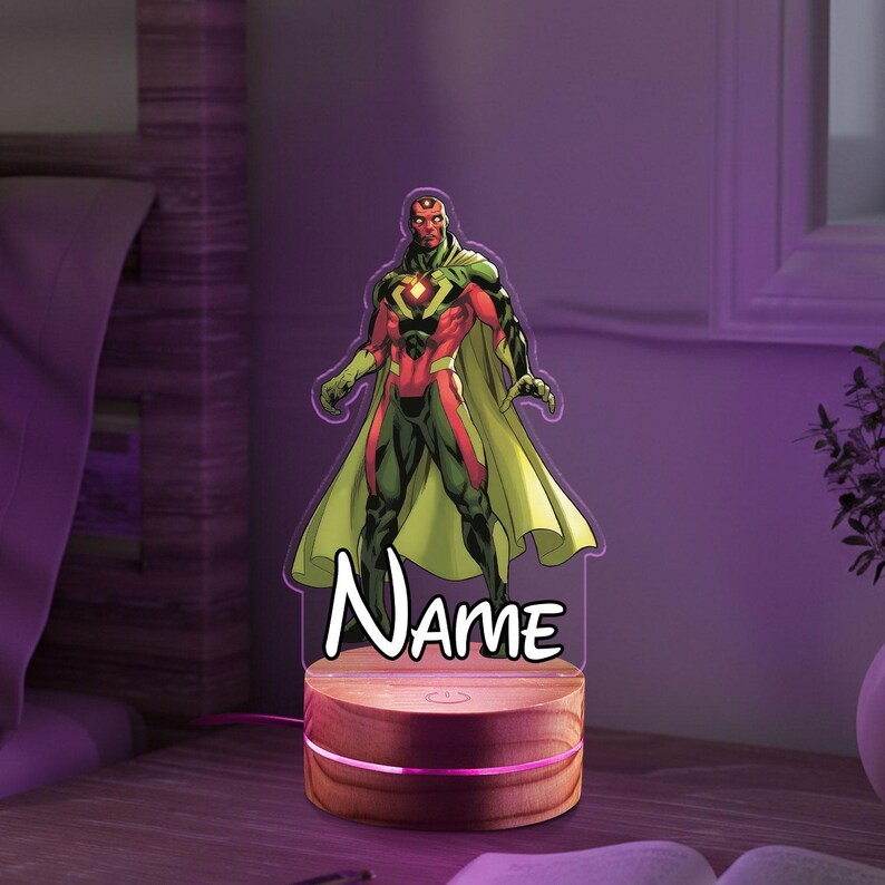 May include: A Vision character night light with a wooden base. The superhero is depicted in a red, green, and black costume with a yellow cape. The word "Name" is written in white script below the character.