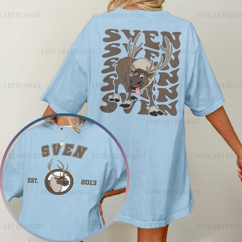 May include: Light blue t-shirt featuring a cartoon reindeer named Sven. The back of the shirt has the name "SVEN" in a repeating pattern with a reindeer graphic. The front has a smaller Sven graphic with "EST. 2013".