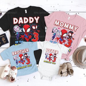 K&ouml;nnte beinhalten: Eine Sammlung von T-Shirts und einem Body zum Thema Spider-Man. Die Shirts sind schwarz, rosa und hellblau und tragen die Aufschriften "Daddy", "Mommy" und "Brother". Der Body ist wei&szlig; und tr&auml;gt die Aufschrift "Peter Birthday Boy". Alle zeigen Spider-Man-Grafiken.