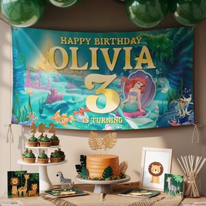 May include: A birthday party scene with a banner that reads "Happy Birthday Olivia 3 is Turning." The banner features an underwater theme with a mermaid. There are cupcakes, a cake, and animal-themed decorations.