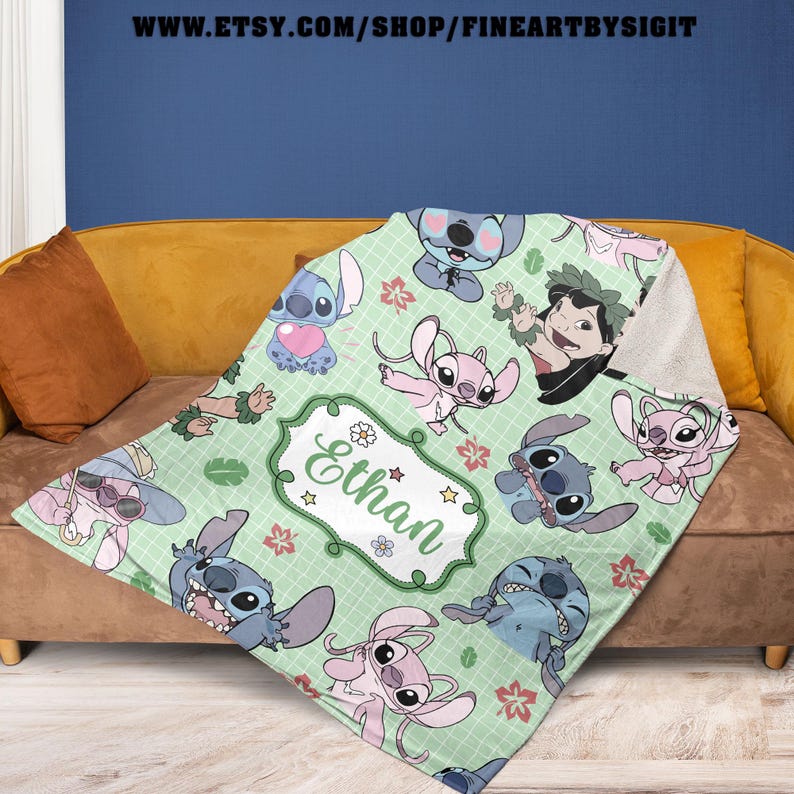 May include: A light green blanket featuring cartoon characters. The blanket has a grid pattern with various images of Stitch and Angel. A white framed label with the name "Ethan" is in the center. The blanket is draped over a brown couch.