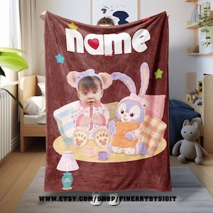 May include: A personalized maroon blanket featuring a child's photo with a cartoon bunny and the word "NAME" in white. The blanket has a heart and star accents, and a lamp illustration.