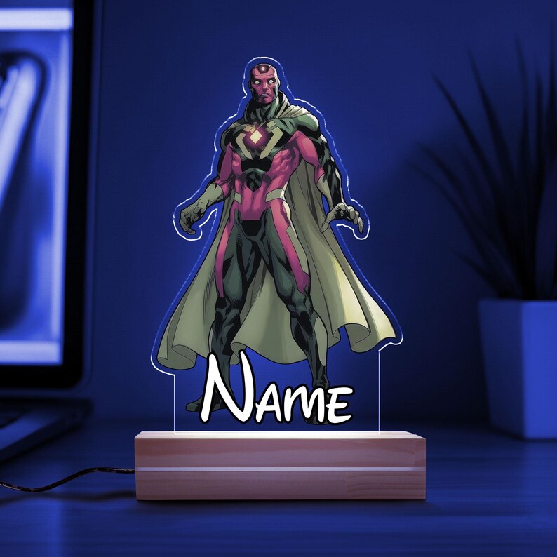 May include: A Vision character-themed LED lamp. The lamp features a colorful illustration of the character with a white outline, mounted on a wooden base. The word "Name" is written in white script. The lamp is plugged in and illuminated with a blue glow.