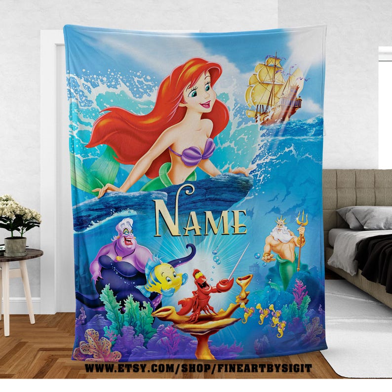 May include: A blue blanket featuring a vibrant illustration of Ariel from The Little Mermaid. The design includes Ariel, Ursula, Flounder, Sebastian, King Triton, and a ship. The word "Name" is displayed prominently. The blanket is suitable for a child's bedroom.