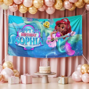 K&ouml;nnte beinhalten: Ein Geburtstagsbanner mit dem Text "HAPPY 4TH BIRTHDAY SOPHIA" mit einer Cartoon-Meerjungfrau, die ein Musikinstrument spielt. Das Banner ist blau mit einem rosa und lila Design. Die Szene umfasst Ballons, einen Kuchen und verpackte Geschenke.