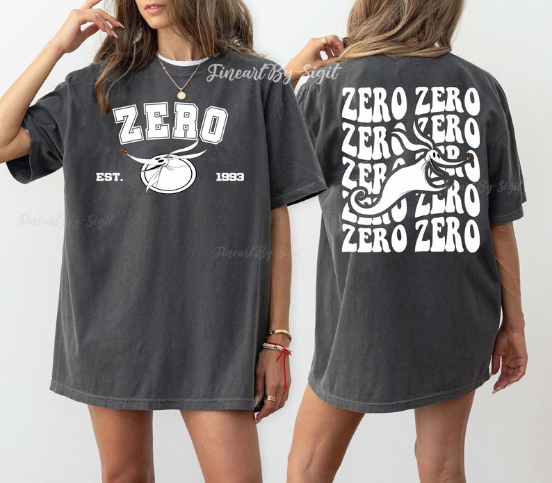 Puede incluir: Una camiseta gris oscuro con un gr&aacute;fico blanco de un fantasma con el texto "ZERO" en una fuente retro. La parte posterior de la camiseta tiene el texto "ZERO ZERO" repetido en una fuente retro con el gr&aacute;fico del fantasma en el centro.