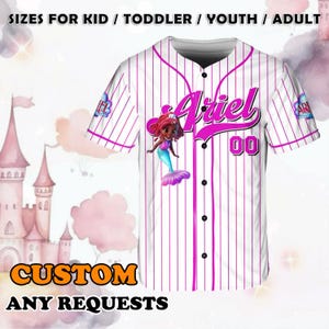 May include: White baseball jersey with pink pinstripes, featuring a cartoon mermaid graphic and the name "Ariel". The jersey includes the number "00" and the text "SIZES FOR KID / TODDLER / YOUTH / ADULT" and "CUSTOM ANY REQUESTS".