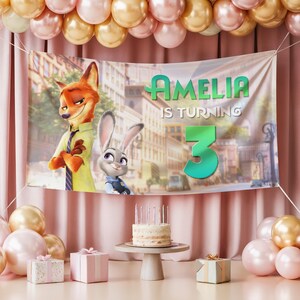 Pu&ograve; includere: Un banner di compleanno con i personaggi Nick Wilde e Judy Hopps di Zootropolis, con la scritta "Amelia compie 3 anni". La scena comprende una torta, regali e palloncini nei toni del rosa e dell'oro.