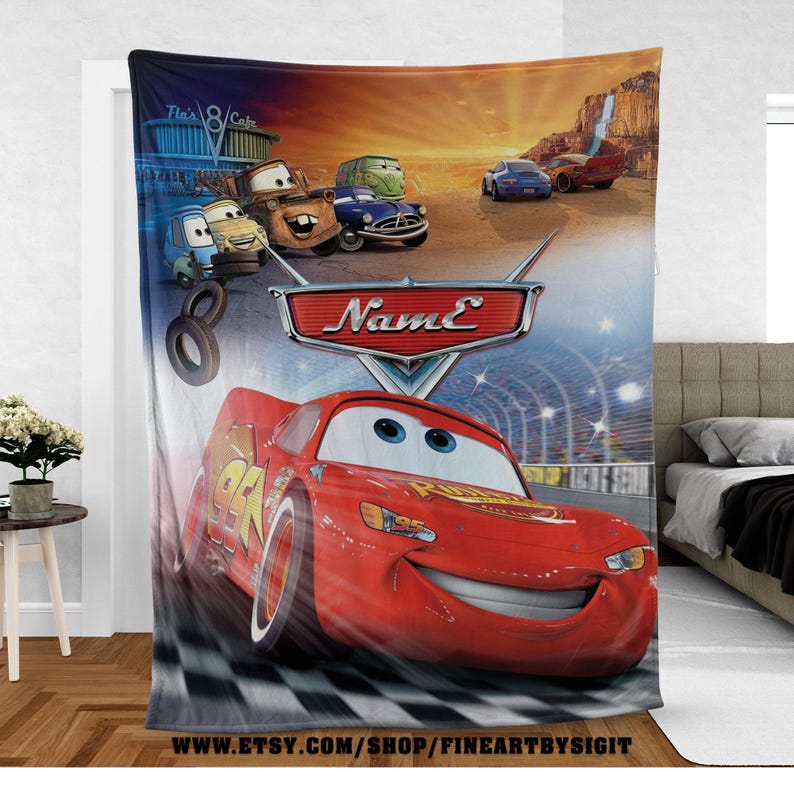 May include: A plush blanket featuring Lightning McQueen from the animated movie Cars. The blanket showcases a vibrant scene with the character on a checkered race track, with other characters and a desert backdrop. The blanket has the text "Name" on it.