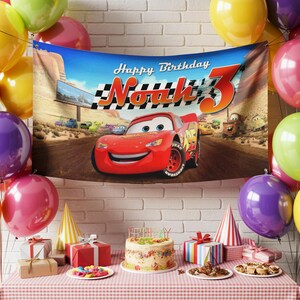 May include: A birthday party scene with a banner featuring Lightning McQueen from the movie Cars. The banner reads "Happy Birthday Noah 3". Colorful balloons, gifts, a cake, and party hats decorate the table. The background is a brick wall.