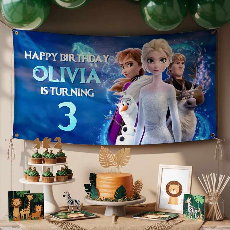 Puede incluir: Escena de fiesta de cumplea&ntilde;os con una pancarta con personajes de la pel&iacute;cula "Frozen" y el texto "Happy Birthday Olivia is turning 3." La mesa incluye cupcakes, una tarta y decoraciones con tem&aacute;tica animal.