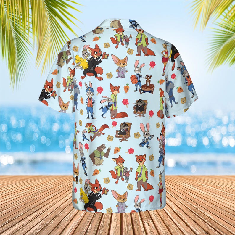May include: A light blue short-sleeve button-down shirt featuring an all-over repeating pattern of cartoon characters from Zootopia, including foxes, rabbits, and other animals, interspersed with small orange carrot and yellow badge icons.