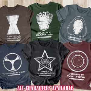Könnte beinhalten: Sechs verschiedene T-Shirts mit Charakteren aus dem Marvel Cinematic Universe's Thunderbolts-Team. Jedes Shirt hat eine abgenutzte weiße Grafik eines Charakter-Logos oder -Symbols, darunter Yelena Belova, Bucky Barnes, Ghost, Taskmaster, Red Guardian und John Walker. Der Text "THUNDERBOLTS" erscheint unter dem Namen oder Logo jedes Charakters.
