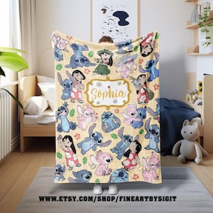 Puede incluir: Una manta beige con personajes de dibujos animados en varias poses. La manta tiene un patr&oacute;n repetido de personajes azules y rosas, con una etiqueta central con marco dorado que dice "Sophia". La manta se muestra en interiores.