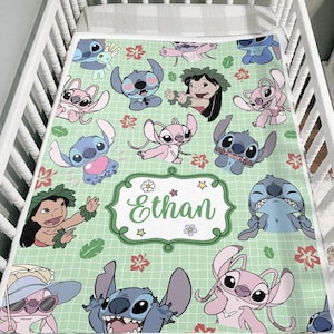 May include: A light green baby blanket featuring cartoon characters and floral designs. The blanket has a grid pattern and a central label with the name "Ethan". The characters are in shades of blue and pink.