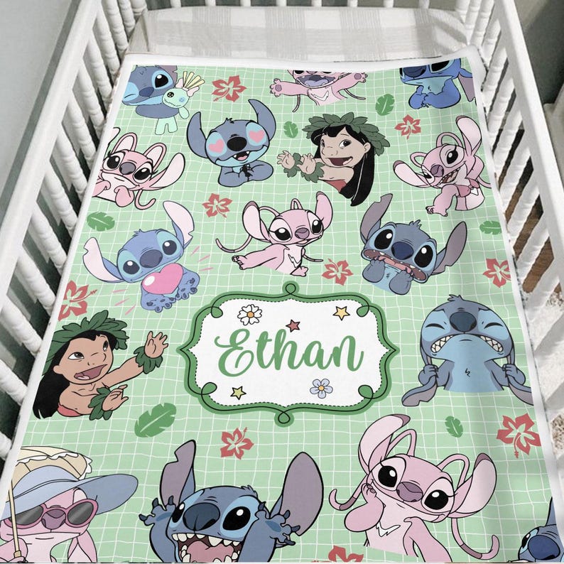 May include: A light green baby blanket featuring cartoon characters and floral designs. The blanket has a grid pattern and a central label with the name "Ethan". The characters are in shades of blue and pink.