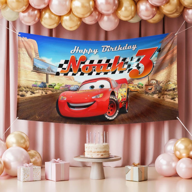 May include: A birthday banner featuring the animated character Lightning McQueen from the movie Cars. The banner reads "Happy Birthday Noah 3" with a checkered flag design. The scene includes a race track and desert landscape.