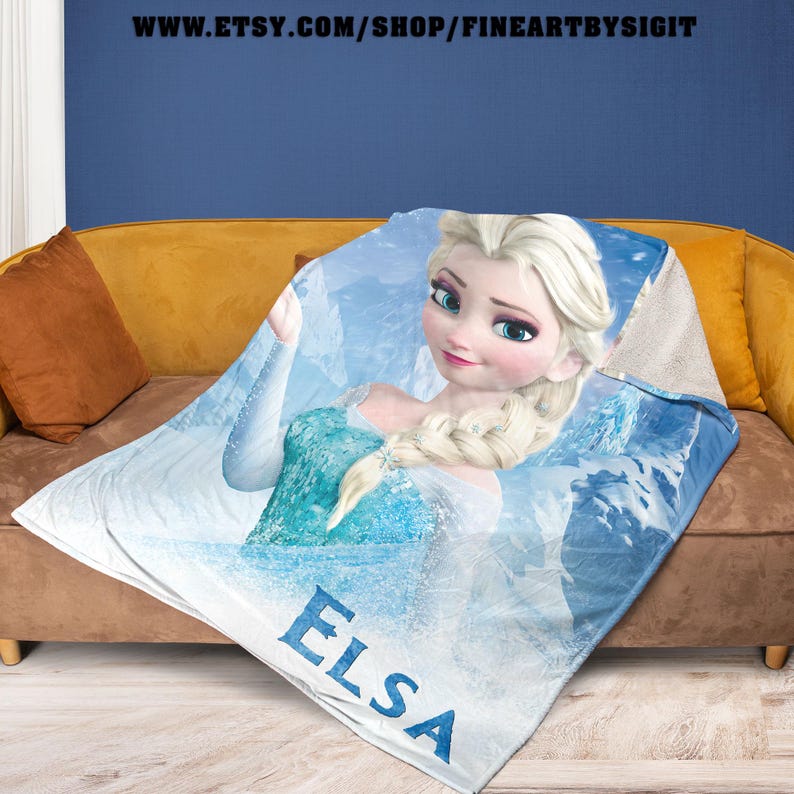 Puede incluir: Una manta blanca y azul con un gr&aacute;fico de Elsa de Frozen. La manta tiene un fondo azul claro con Elsa con un vestido azul. La palabra "ELSA" est&aacute; impresa en azul en la parte inferior. La URL de la tienda Etsy es visible en la parte superior.