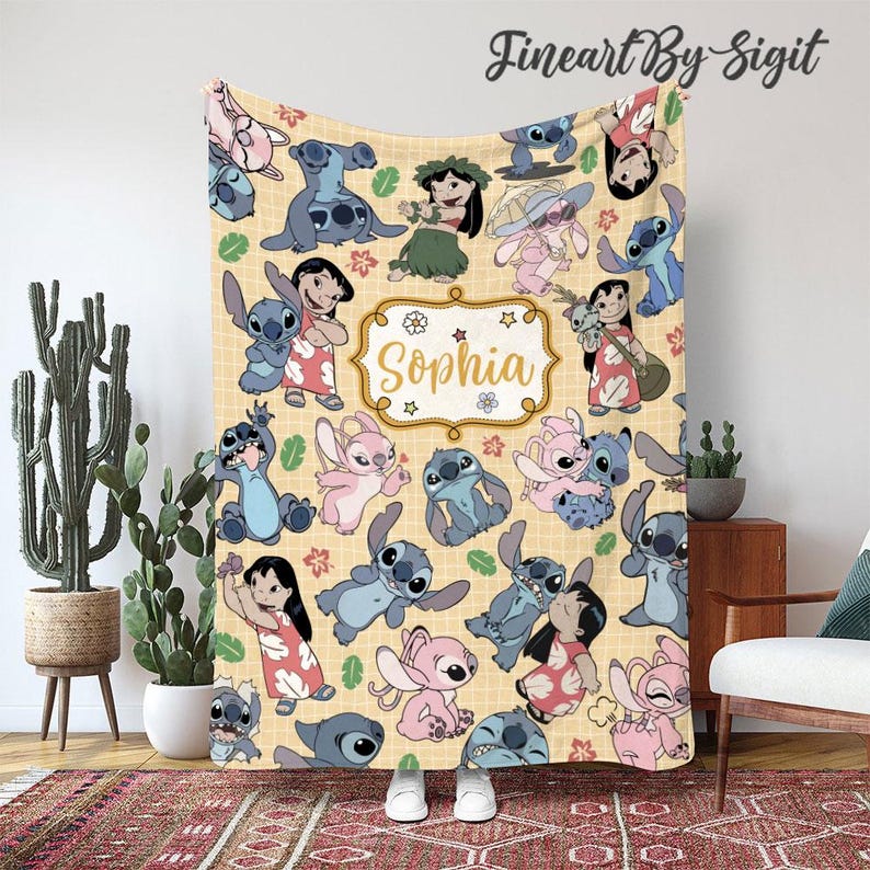 Puede incluir: Una manta beige con un patr&oacute;n repetido de personajes de dibujos animados y el nombre "Sophia" en un marco decorativo. La manta presenta personajes en azul, rosa y otros colores, con hojas y estrellas.