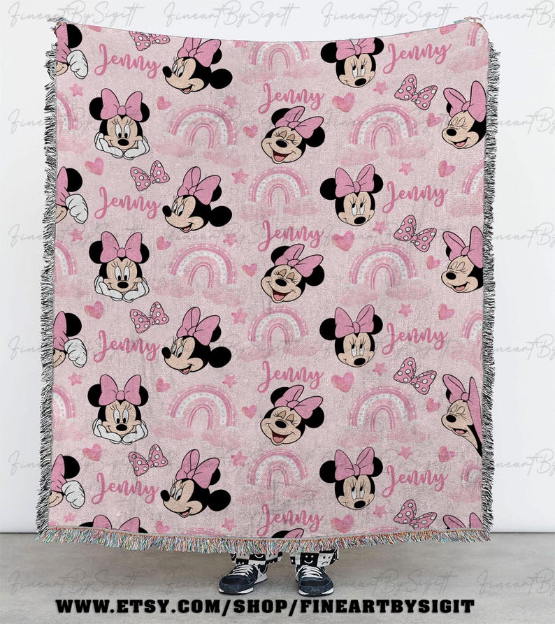 K&ouml;nnte beinhalten: Rosa gewebte Decke mit Minnie Mouse-Gesichtern, Schleifen, Regenbogen und Herzen. Der Name "Jenny" ist wiederholt im Design enthalten. Die Decke hat einen Fransenrand und ist f&uuml;r ein Kinderzimmer geeignet.