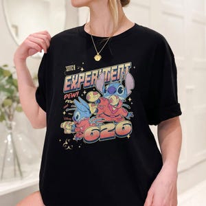 May include: Black t-shirt with a graphic print of Stitch from Lilo & Stitch. The graphic features Stitch in a spacesuit with the text "Experiment 626" and "Pew! Pew!"