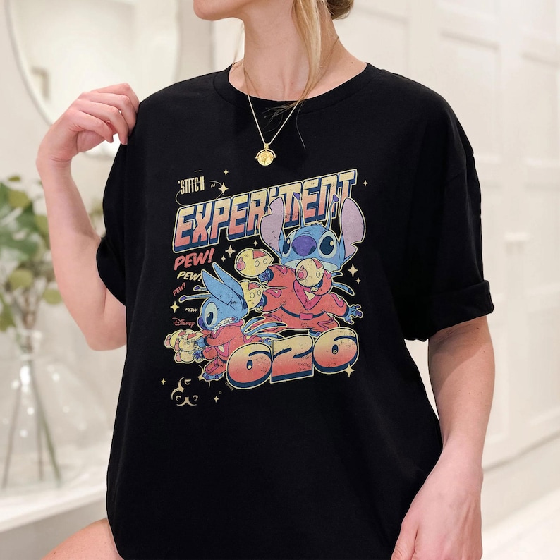 May include: Black t-shirt with a graphic print of Stitch from Lilo & Stitch. The graphic features Stitch in a spacesuit with the text "Experiment 626" and "Pew! Pew!"
