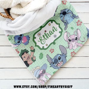 May include: A personalized baby blanket featuring cartoon characters on a light green background. The blanket has a white sherpa backing and a design with the name "Ethan" in a decorative frame. The blanket is decorated with cartoon characters.