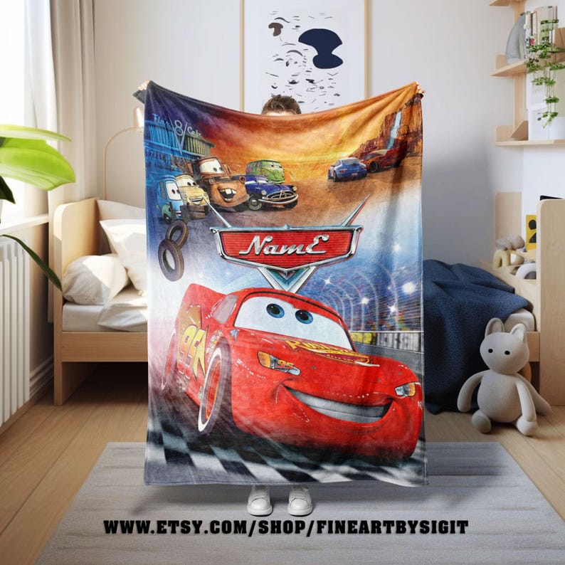 May include: A colorful Cars-themed blanket featuring Lightning McQueen and other characters. The blanket has a vibrant design with the text "Name" and the website address www.etsy.com/shop/fineartbysigit.