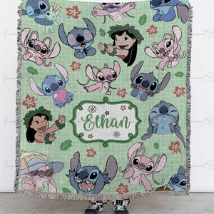 May include: A light green throw blanket featuring cartoon characters, including Stitch and Lilo, with floral and leaf accents. The blanket has a personalized name, "Ethan", in a decorative frame. The blanket has a fringed edge.
