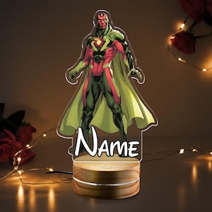 May include: A Vision character night light with a wooden base. The superhero is depicted in his classic red, green, and yellow costume. The word "Name" is written in a stylized font on the front of the light.