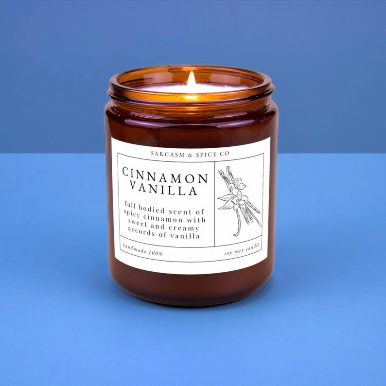 K&ouml;nnte beinhalten: Ein braunes Glasgef&auml;&szlig; mit einer Kerze und einem wei&szlig;en Etikett mit der Aufschrift "SARCASM & SPICE CO CINNAMON VANILLA full bodied scent of spicy cinnamon with sweet and creamy accords of vanilla handmade 100% soy wax candle".