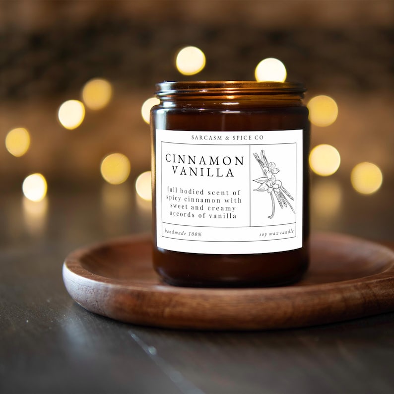 K&ouml;nnte beinhalten: Ein braunes Glasgef&auml;&szlig; mit einer Kerze und einem wei&szlig;en Etikett mit der Aufschrift "SARCASM & SPICE CO CINNAMON VANILLA full bodied scent of spicy cinnamon with sweet and creamy accords of vanilla handmade 100% soy wax candle".