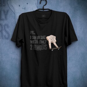 Puede incluir: Camiseta negra con un gráfico blanco de una mano haciendo skate con el texto "Pff... Puedo hacer eso con solo 2 dedos."
