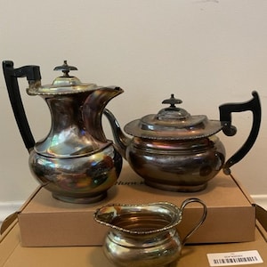 May include: A silver tea set with a teapot, creamer, and sugar bowl. The set has a classic design with a shiny finish.