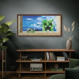 May include: A framed pixel art print featuring a Minecraft Creeper in a beach scene with blue skies and water. The artwork is in a brown frame and hangs on a dark green wall. The print is a rectangular shape.