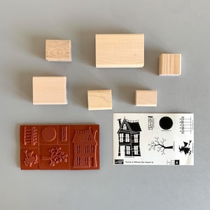 May include: A collection of wooden stamps and a sheet of stamp designs. The stamps are various sizes and shapes. The stamp designs include a haunted house, a tree, a witch, and the text "Home Is Where the Haunt Is."
