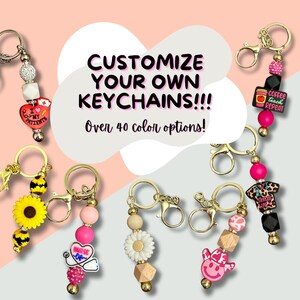 May include: Assortment of colorful beaded keychains with various charms, including a sunflower, a daisy, a cowboy hat, a nurse's stethoscope, and a coffee cup. The text "CUSTOMIZE YOUR OWN KEYCHAINS!!! Over 40 color options!" is displayed above the keychains.