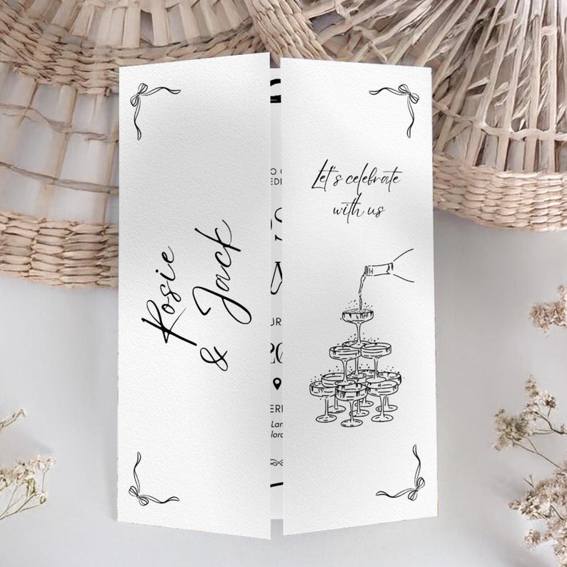 May include: A white wedding invitation card with black script that reads "Rosie & Jack" and "Let's celebrate with us." The card features a champagne tower illustration and decorative bow accents. The card is folded.