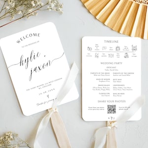 Może przedstawiać: Dwie białe karty wachlarzowe ślubne z czarnym tekstem. Jedna mówi "Witamy na ślubie Kylie + Jaxon" i datę. Druga ma oś czasu, szczegóły przyjęcia weselnego i kod QR. Obie mają kremową wstążkę.