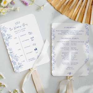 May include: Two wedding fan programs with blue floral designs and text. One fan reads "Our Wedding Day" with the couple's names and date. The other lists the ceremony details and wedding party. Both have cream-colored ribbons.