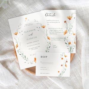 May include: Wedding invitation suite featuring a floral design with a wreath of green leaves and orange flowers. The invitation card reads "Eleanor and Gareth" with the wedding date and location. The RSVP card has a floral design and a space to fill in the guest's name and response.