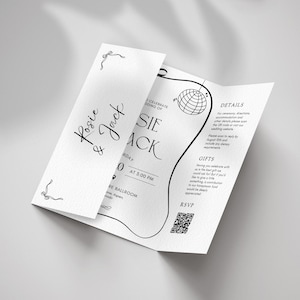 May include: A white wedding invitation with black text and decorative line art. The invitation is folded and features the names "Rosie & Jack", event details, and a QR code for RSVP.